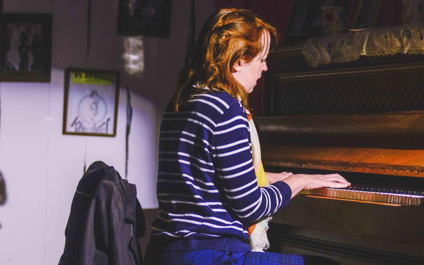 Victoria Brazier playing the piano in Crossings by Deirdre Kinahan