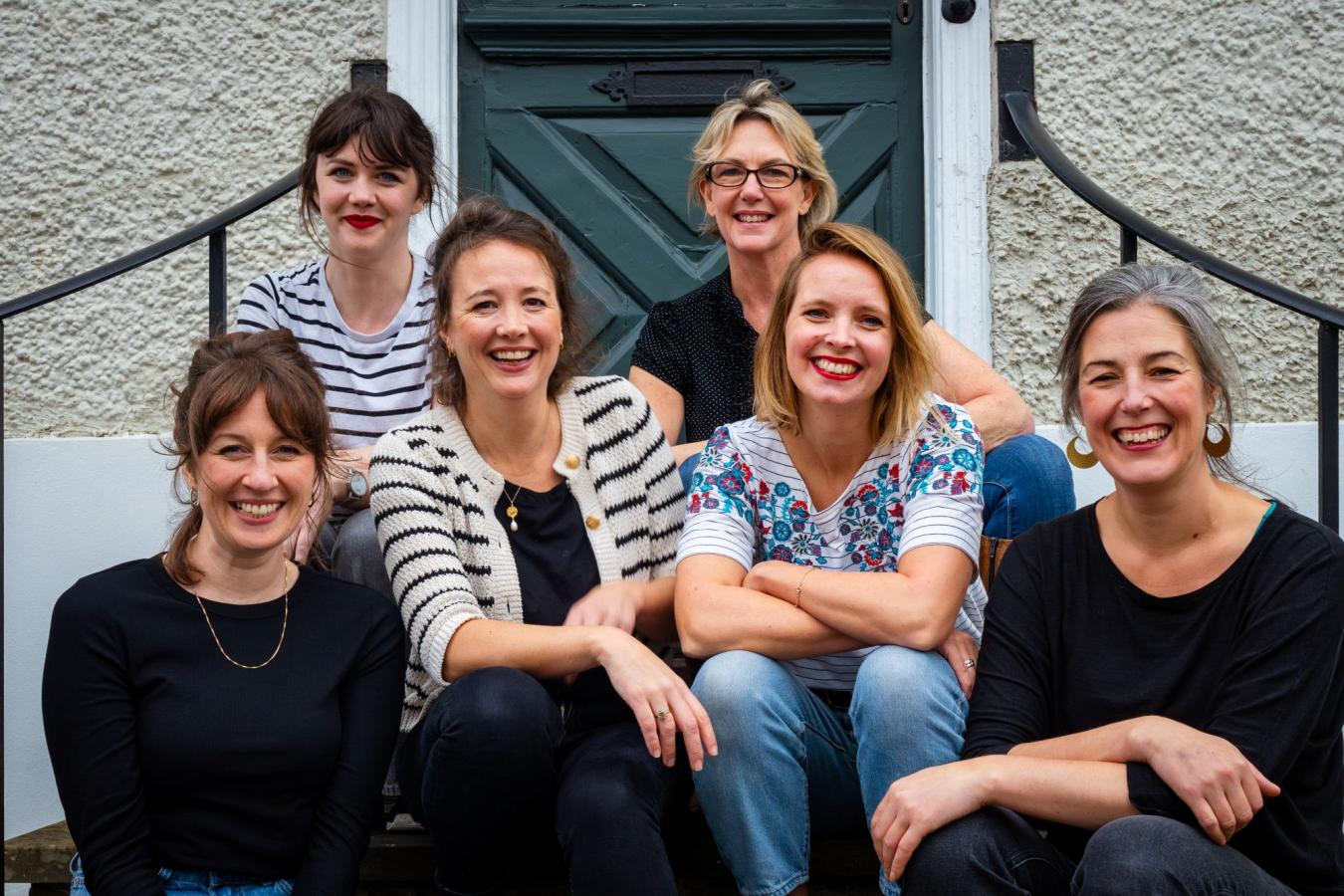 Pentabus team sit on steps outside a house in Ludlow