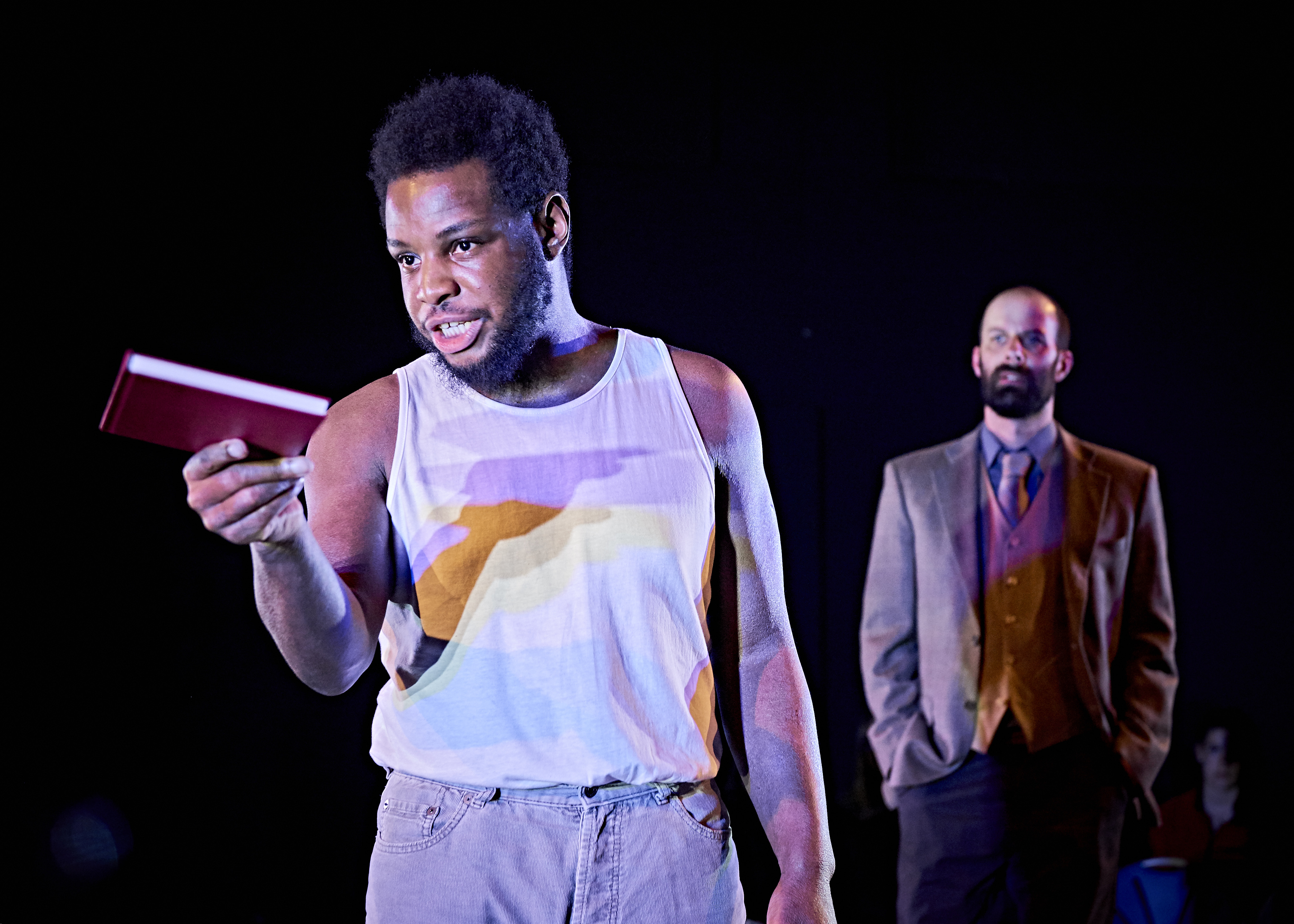 A man stands on stage holding a book