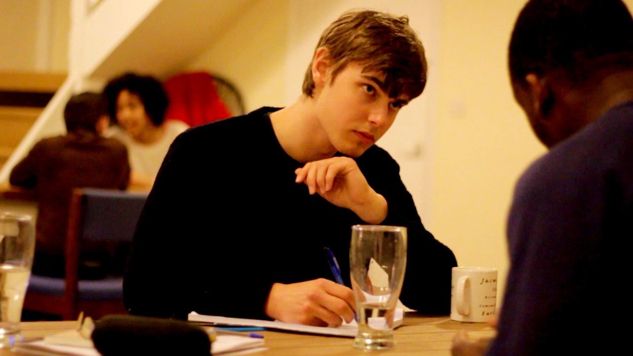 Young people sit at a table together, writing