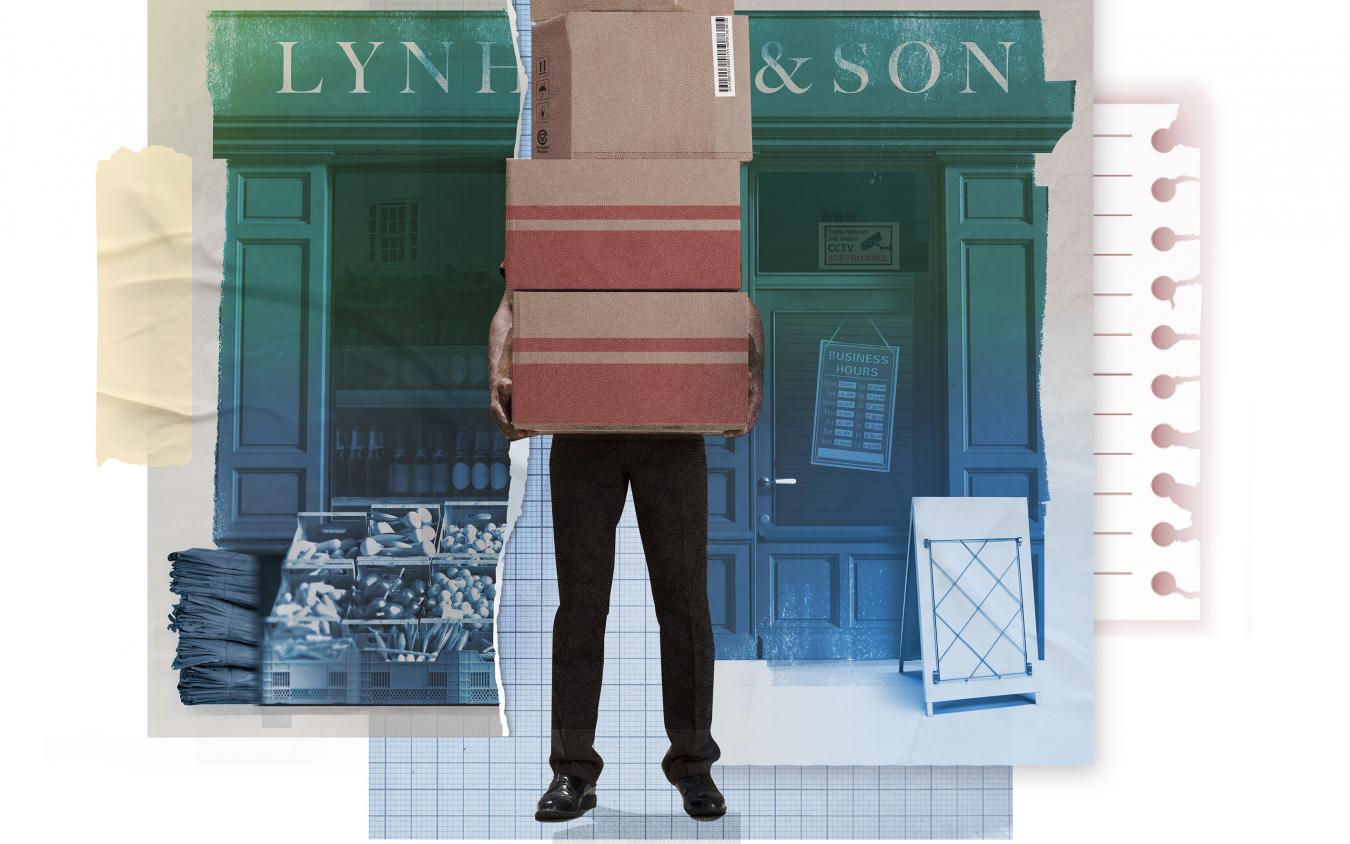 Man holding boxes which hide his face standing in front of a corner shop