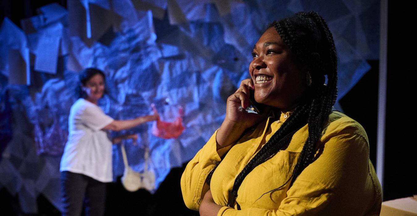 On stage, a smiling actress holds a mobile phone